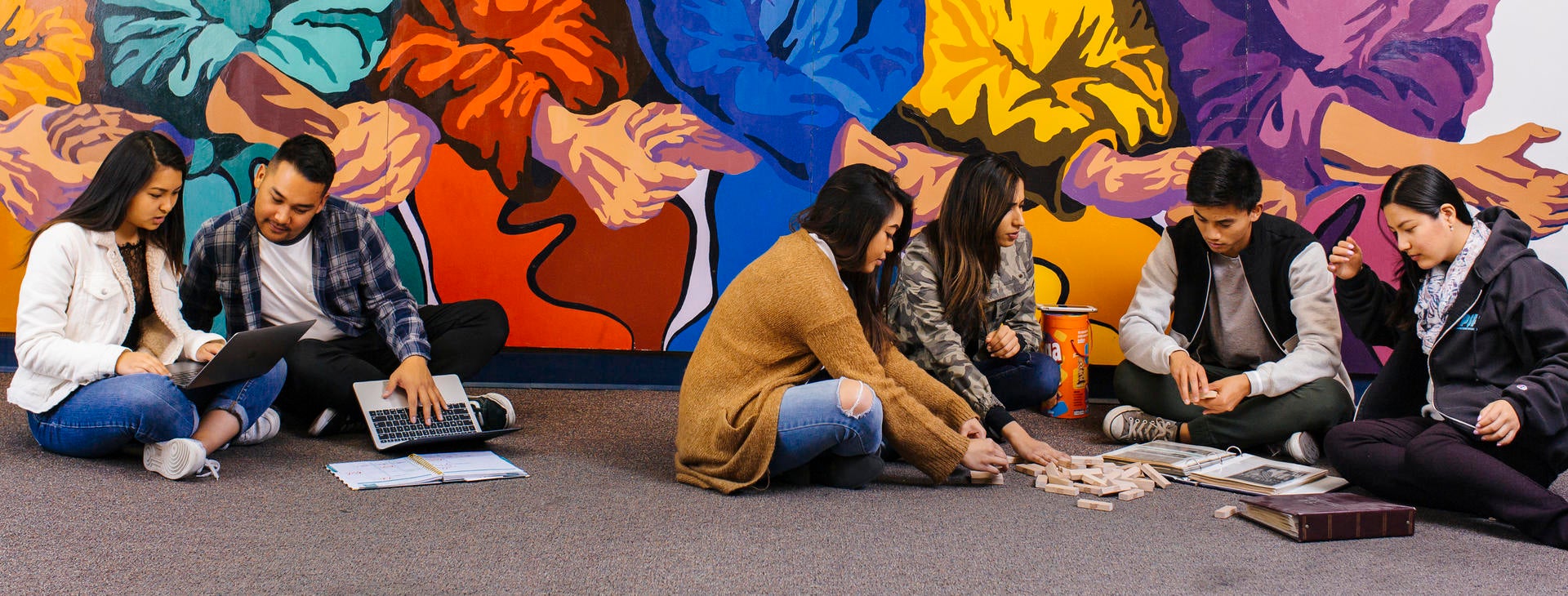 Students studying in front of the Asian Pacific Student Programs mural