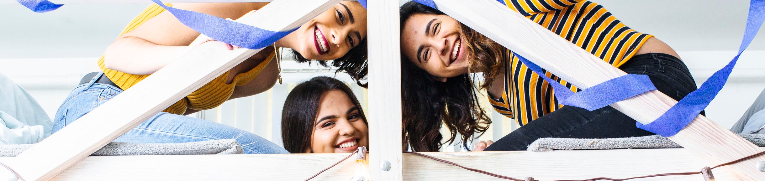 Three students smiling in a lofted dorm area