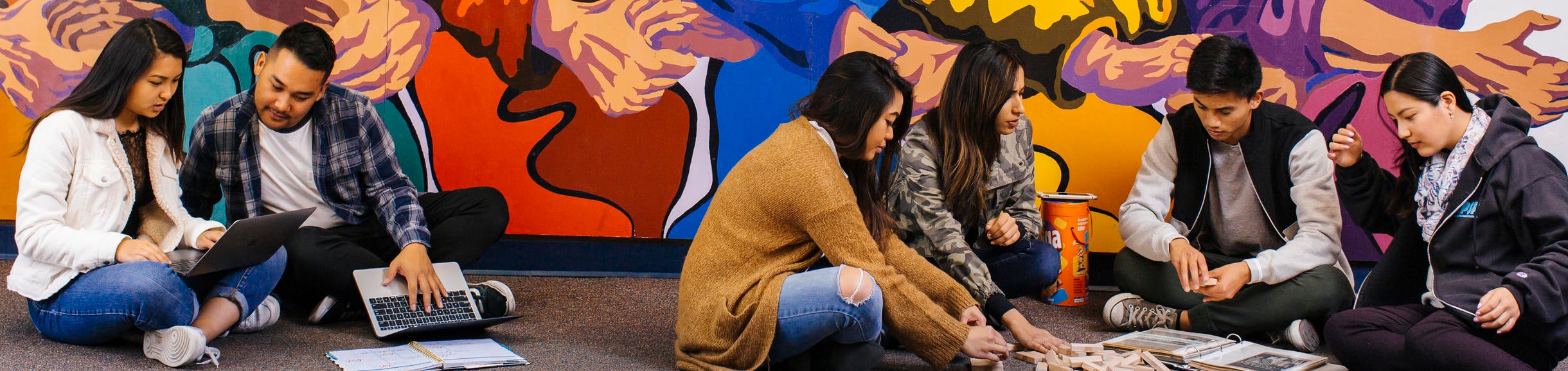 Students studying in front of the Asian Pacific Student Programs murals