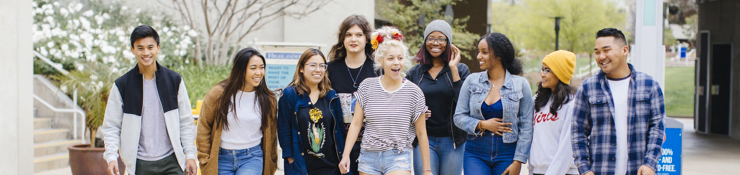 A group of students walking, talking, and smiling outside of Costo Hall on the UC Riverside campus.